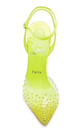 a pair of neon yellow stiletto heels with a crystal embellished toe. the shoes are pointed toe and have a clear strap going around the ankle. the shoes are from the designer label, christian louboutin.