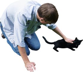a man is kneeling down and petting a black cat on the grass. the man is wearing a plaid shirt and jeans, and the cat is looking up at him with affection. they both seem very happy.