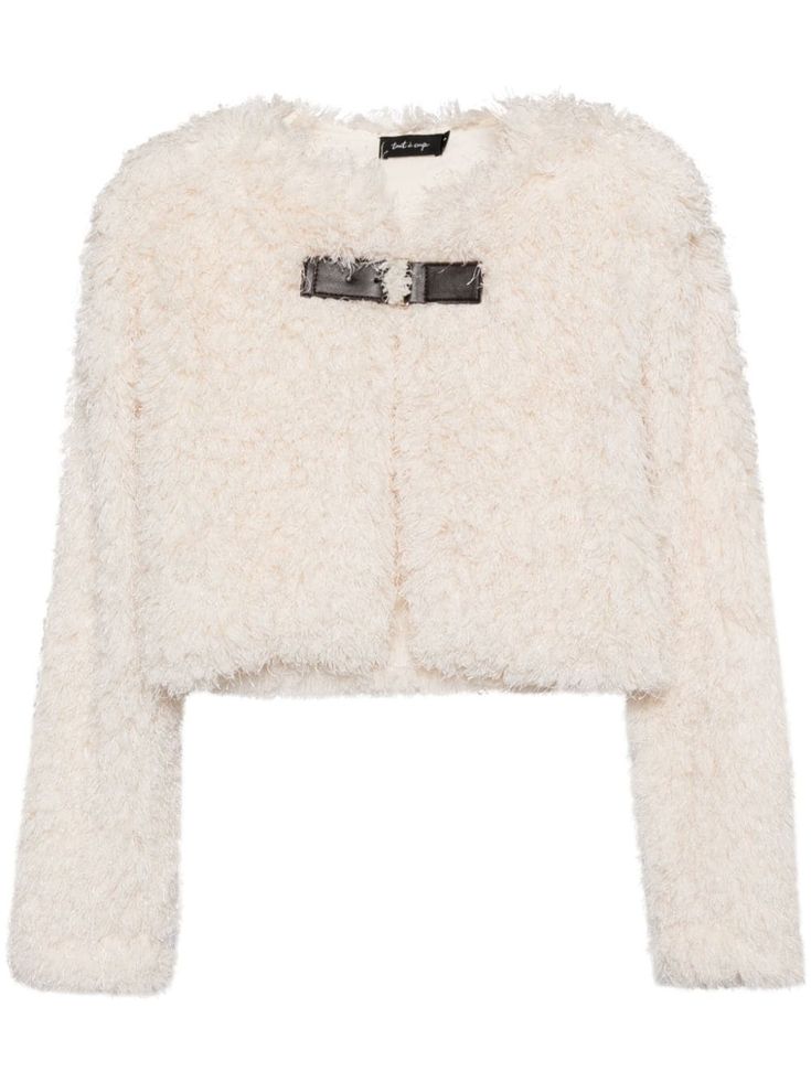 a white faux fur jacket with a fluffy texture. the jacket has a cropped length and long sleeves. there is a small black buckle detail on the front of the jacket. the jacket is perfect for staying warm and stylish in the winter.