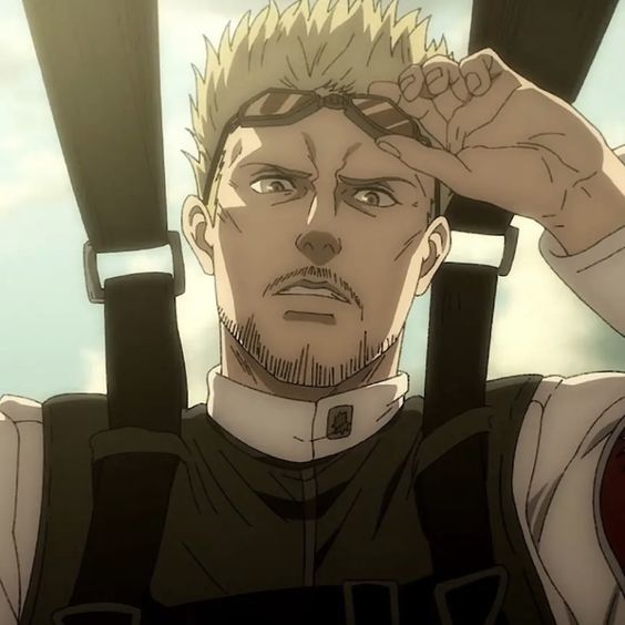 the image shows a closeup illustration of a blondhaired, bearded man from an anime. he has a serious expression on his face and is wearing a white militarystyle uniform and has on goggles that he is pushing up with his right hand. he appears to be strapped into a harness. the background is blurred, suggesting he is in motion. the color palette is muted, with a focus on browns and tans. the overall impression is one of intensity and determination.