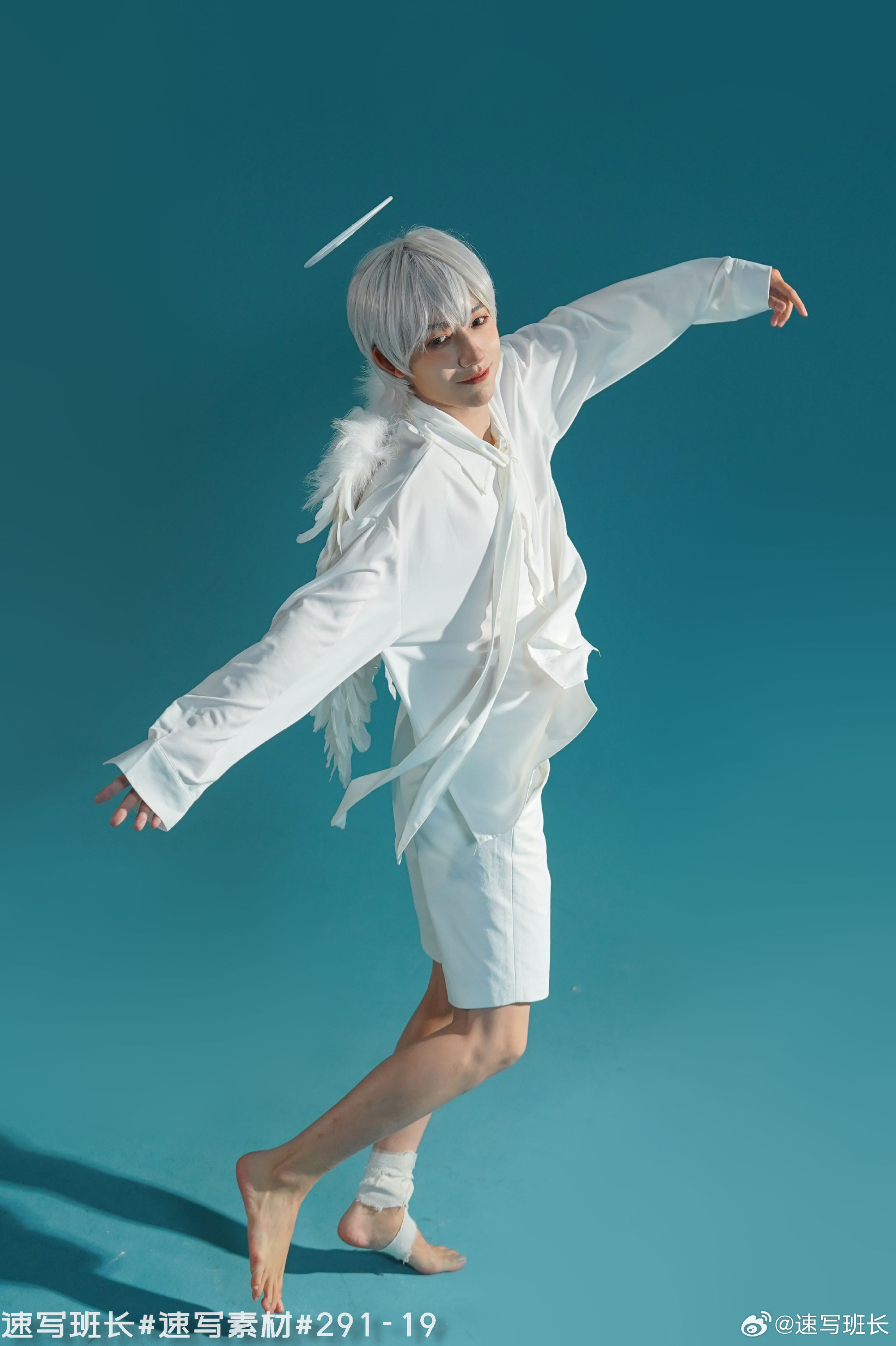 a man with white hair is wearing a white outfit and angel wings, posing against a light blue background. there is a halo above his head. the image is welllit, suggesting studio lighting.  the man is striking a graceful pose, extending his arms and legs. his expression is one of serenity.  the overall aesthetic is ethereal and angelic.