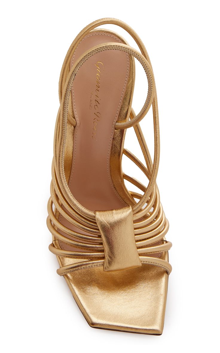 a pair of gold giuseppe zanotti cassandra heels are shown.  they are high heels with a strappy design.  the shoes are made of metallic leather.  the shoes are shown against a white background.