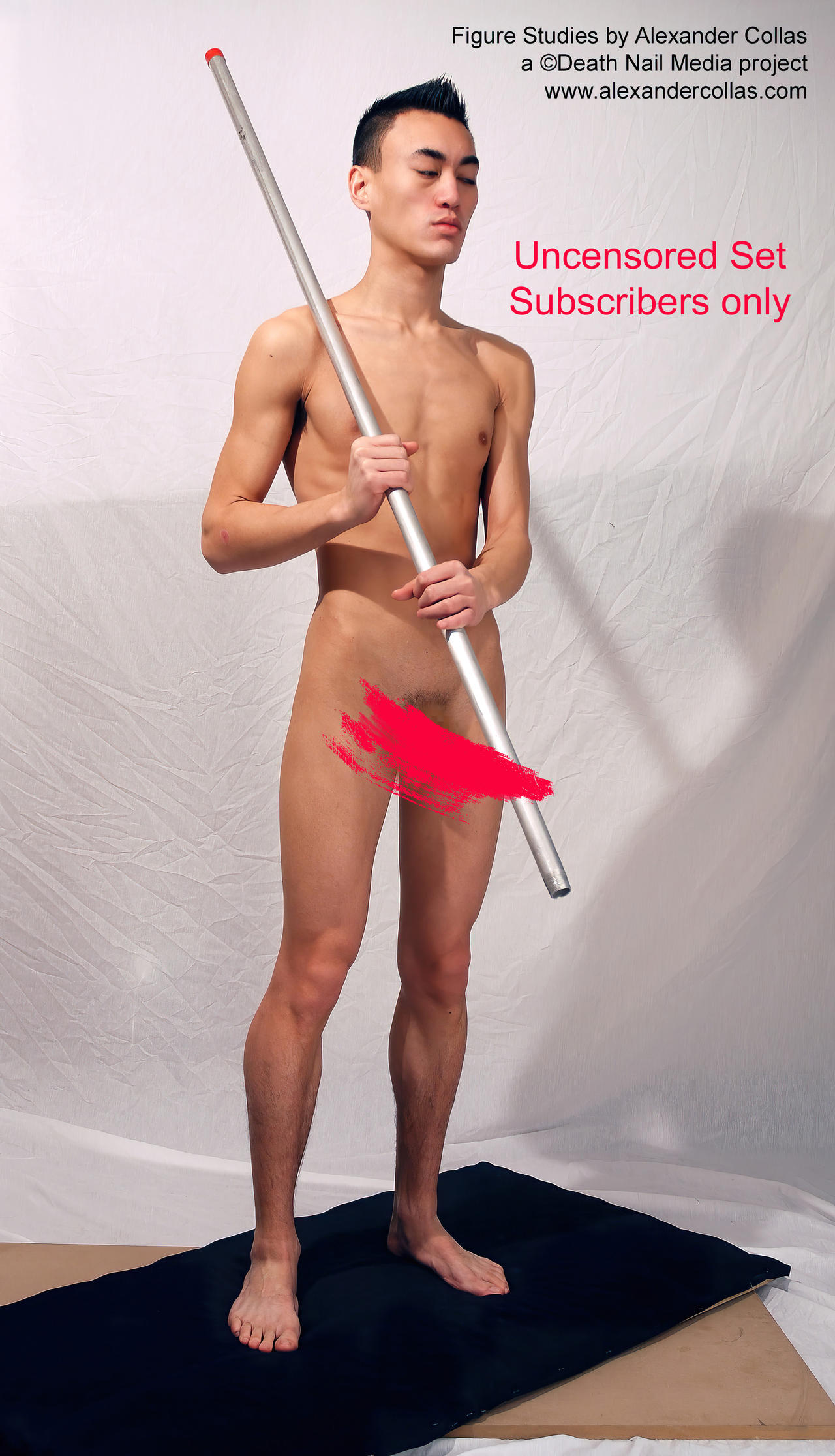 full shot photograph of a young, slender, nude male figure standing and holding a long pole. the model is posed in a relaxed stance, with his weight distributed evenly on both legs. the background is a plain white backdrop. a red censor bar obscures part of his genitalia. text overlays indicate that the image is a "figure study by alexander collas," a "death nail media project," and that the set is "uncensored" and "subscribers only."