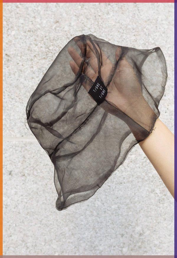 a black sheer hat with a tag that says "1/gre ft 1/gre."  the hat is being held by a hand, with the background out of focus.  the hat is likely made of a fine mesh material, giving it a delicate and airy appearance.