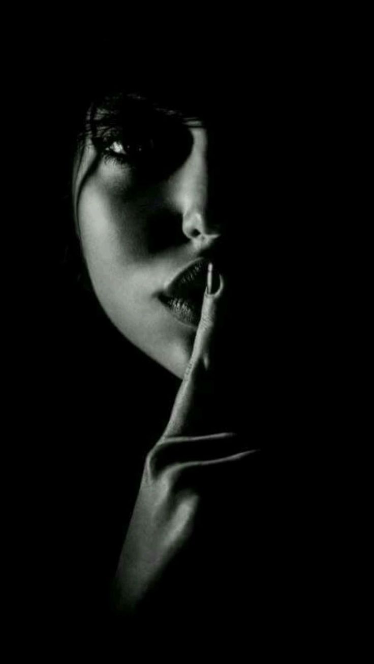 a black and white portrait of a woman's face, her finger placed on her lips