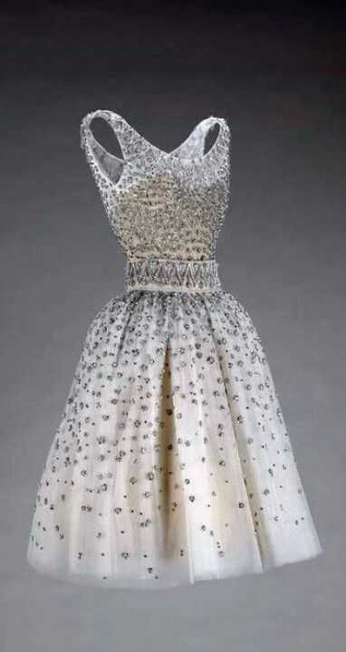 a white tulle dress with beaded sequins. the dress has a fitted bodice and a full skirt. it is a vintage style dress that would be perfect for a special occasion, such as a prom or a wedding.