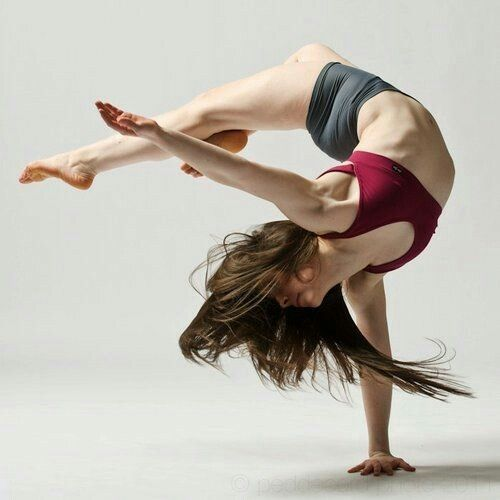a woman in activewear executes a graceful and challenging dance pose against a white studio background. the image captures her flexibility and strength, highlighting the artistry of movement.  the soft lighting and side perspective enhance the feeling of motion.