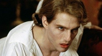 a close up shot of a man with blond hair looking directly at the camera. he's wearing a white shirt with the collar up and has a serious, intense expression on his face.