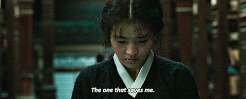 a woman wearing a hanbok looks down with a serious expression. the text "the one that saves me" is overlaid at the bottom of the image. the woman stands indoors in front of wooden shelves full of books.