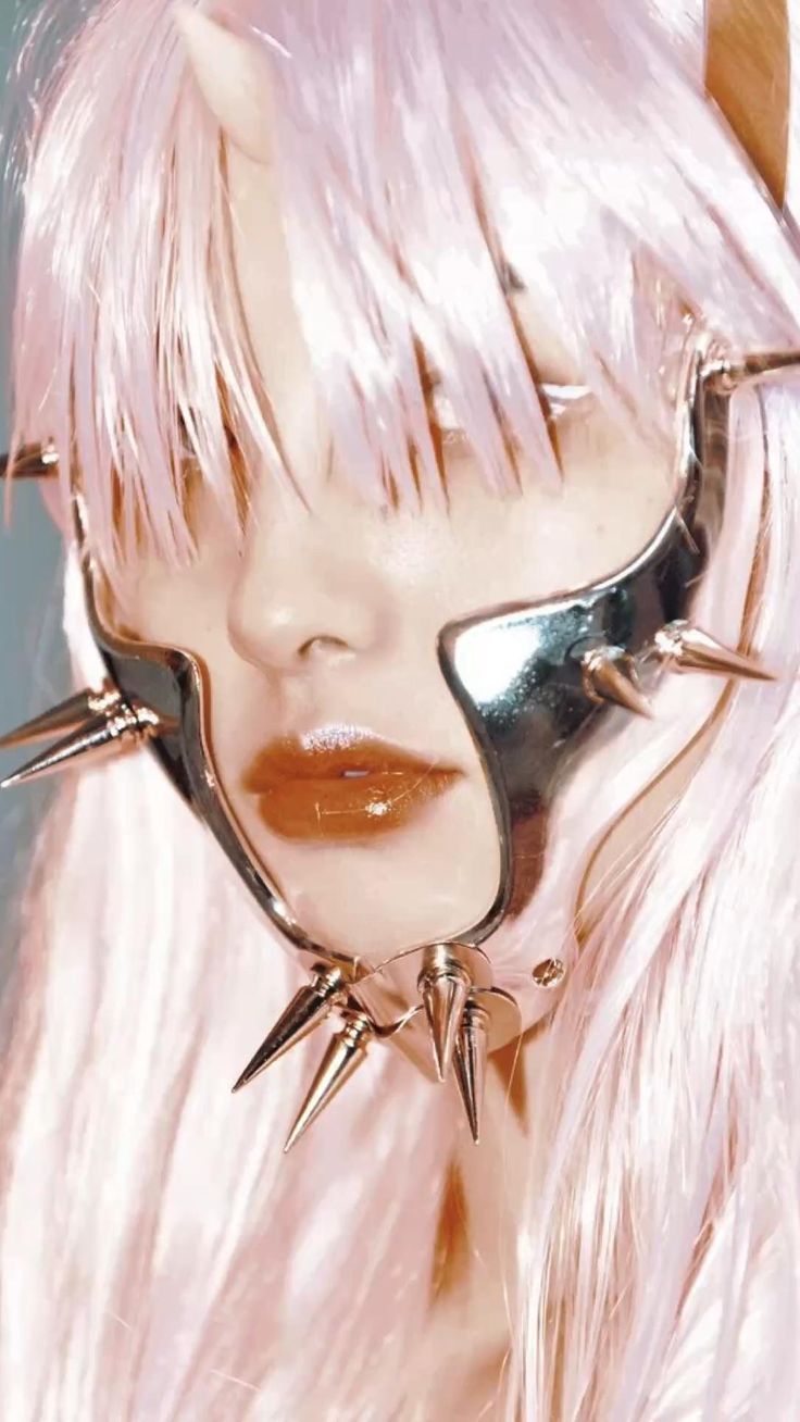 a closeup portrait of a woman with pink hair wearing a glamorous futuristic metal accessory with spikes on her face. she's staring into the camera with a cool and bold expression. the accessory reflects light, highlighting her features and adding a touch of edgy chic to her look.