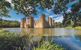 a majestic medieval castle, constructed from weathered stone, stands proudly amidst a tranquil lake. its sturdy towers and ramparts, softened by the passage of time, exude an aura of strength and history. lush green trees frame the scene, their foliage mirrored in the still waters, enhancing the sense of peace and serenity. the azure sky, punctuated by fluffy white clouds, completes the picturesque setting.