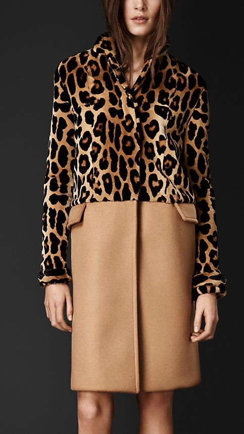 a woman is wearing a coat. the coat has a leopard print on the upper portion and tan fabric on the lower portion. she has long sleeves.
