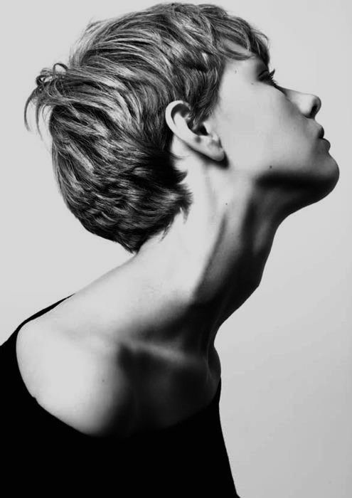 a black and white studio shot of a person with short hair looking up. the focus is on their neck, shoulder, and face. the person is wearing a dark shirt. the image is a closeup, highlighting the details of their features.