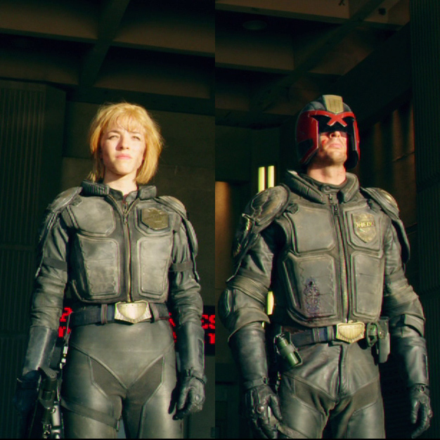this image showcases a female and male figure clad in futuristic armor, standing side by side with serious expressions on their faces. the male figure, resembling the iconic judge dredd character from the science fiction franchise, wears a black helmet with a red visor and a black leather armor suit. he holds a gun in his right hand and is looking straight ahead, suggesting a law enforcement or justicefocused role.  the female figure, also dressed in a leather armor suit with a sleek design, has short blonde hair. she is looking directly ahead, her expression reflecting a determination and preparedness. the background hints at a dystopian setting with concrete walls and lighting that accentuates the figures. the overall composition portrays a dynamic and actionpacked scene, likely from a science fiction movie or television show.