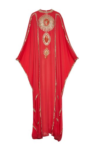 a red, embroidered kaftan dress on a white background. the dress is embellished with gold detailing. the dress has long sleeves and a capelike design.