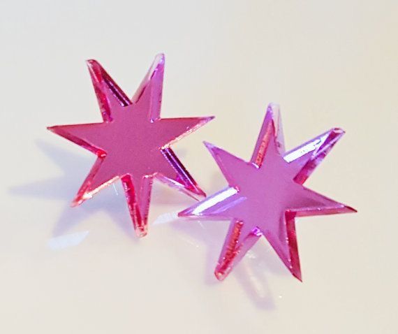 two shiny pink starburst earrings are displayed on a white surface.