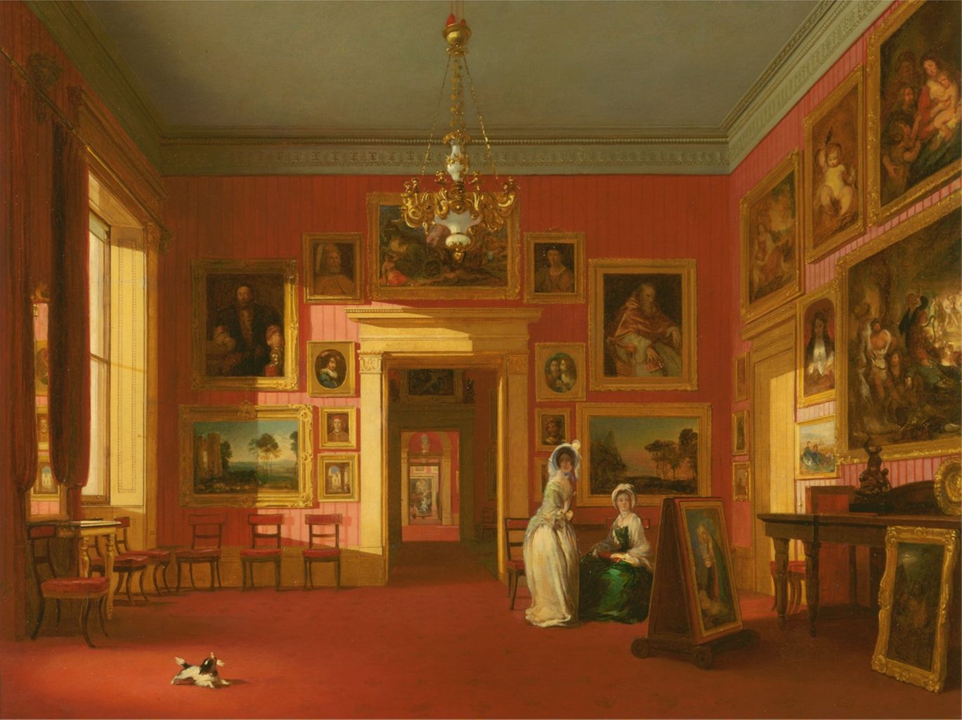 the painting depicts the interior of an art gallery with red walls and a red carpet. the walls are covered in numerous paintings of various sizes and styles. in the center of the room, two women are standing, one in a white dress and the other in a green dress. a small dog is lying on the floor in the foreground. a doorway leads to another room, creating a sense of depth. a chandelier hangs from the ceiling, and sunlight streams in through a window on the left side of the painting. furniture such as tables and chairs are scattered throughout the room.