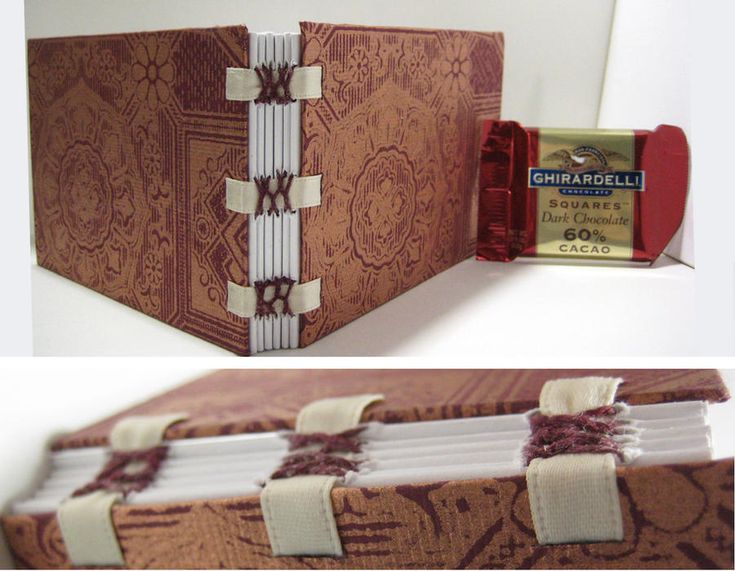 the image shows a handmade book or journal with an exposed spine and stitched binding. the cover is made of brown fabric with a decorative pattern. the binding is secured with ribbons. a ghirardelli dark chocolate square is positioned next to the book.