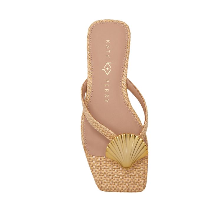 the image shows a pair of women's katy perry sandals. the sandals are light beige, made of woven strawlike material, and have a gold shellshaped accent on the toe strap.  the sandals are thongstyle flipflops with a flat sole.  the insole displays the "katy perry" brand name. the sandals are presented against a white background, showcasing a clear view of the shoe's details and design.