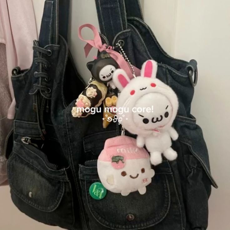 a denim hobo bag with a collection of cute keychains, including a bunny, a character wearing bunny hood, a milk carton, and an anime cat. the bag is adorned with pockets and zippers, creating a playful and trendy look.