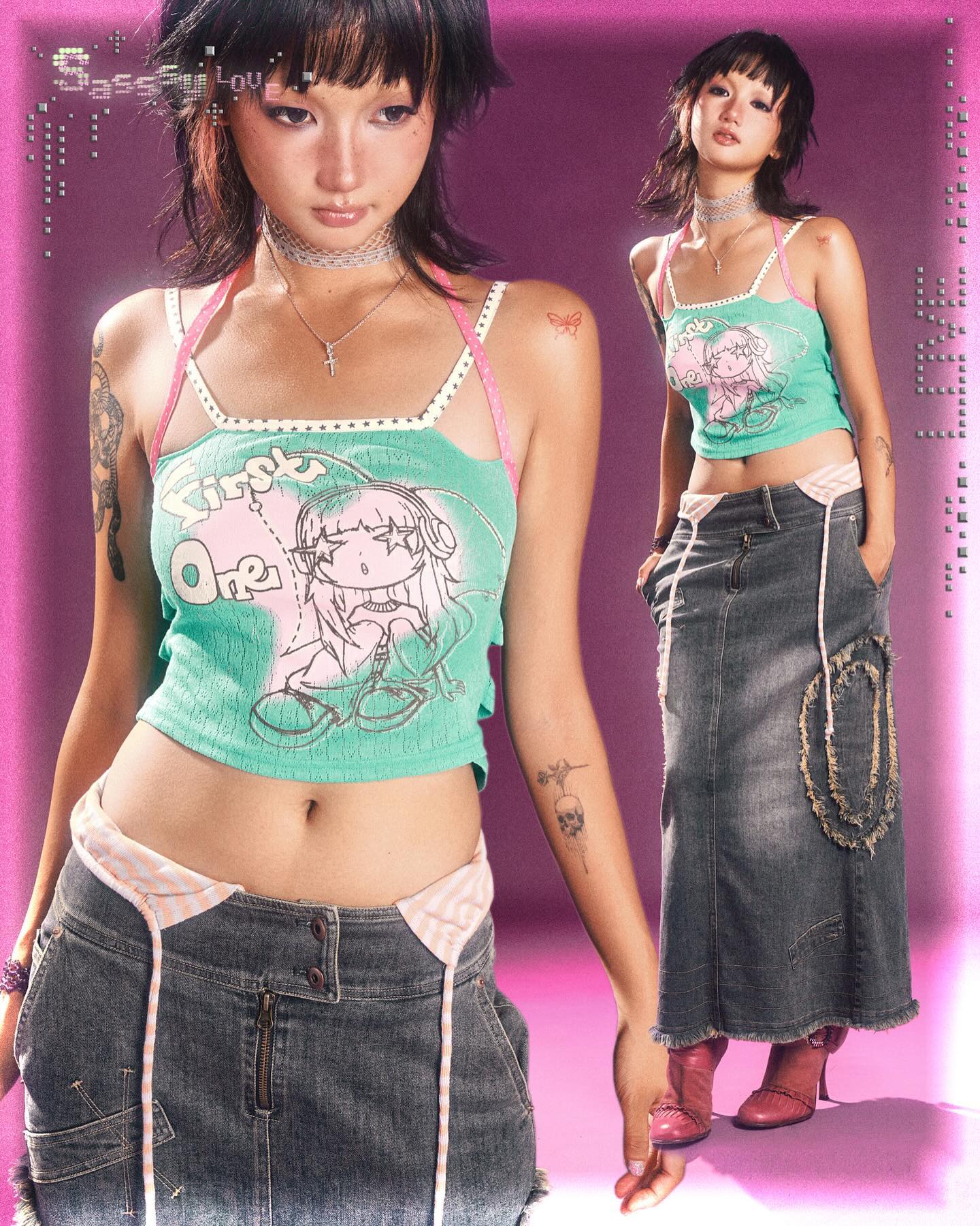 the image is a fashion photograph featuring two young women showcasing similar outfits against a pink background.  the style is heavily influenced by y2k and 90s fashion trends, combining elements of grunge and kawaii aesthetics. both models wear a cropped, pastel green tank top featuring an animestyle cartoon graphic.  the tops have delicate straps and subtle studded details. the bottom half of their outfits consists of long, dark denim skirts—one is a maxi skirt with distressed details and the other is a shorter layered denim skirt with pink and white accents. both models also wear chokers and have subtle tattoos.  one model's skirt is styled to create a more layered look. the overall vibe is playful and slightly rebellious. the image is stylized with a slightly grainy, vintage filter.