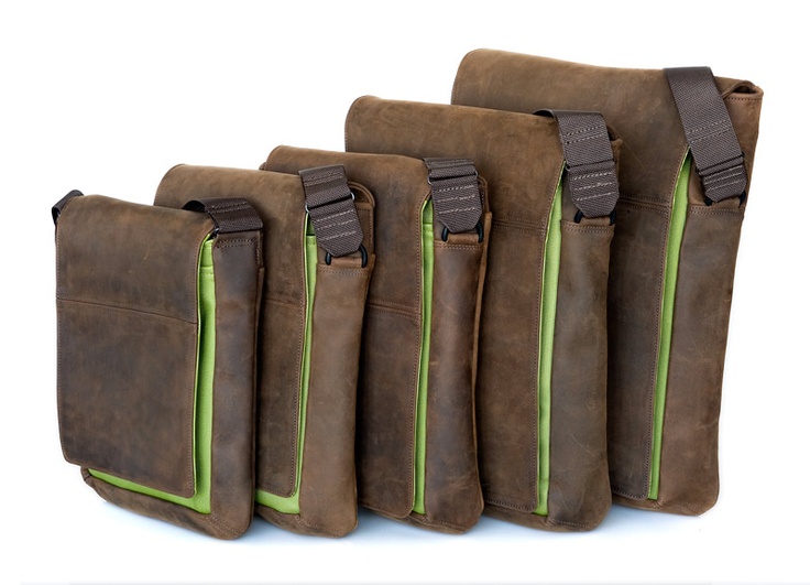 four brown leather messenger bags of varying sizes with green trim are lined up from largest to smallest. they are all  designed with a strap that goes over the shoulder.  the bags appear to be made of a distressed or vintage leather.  the image is shot against a white background.