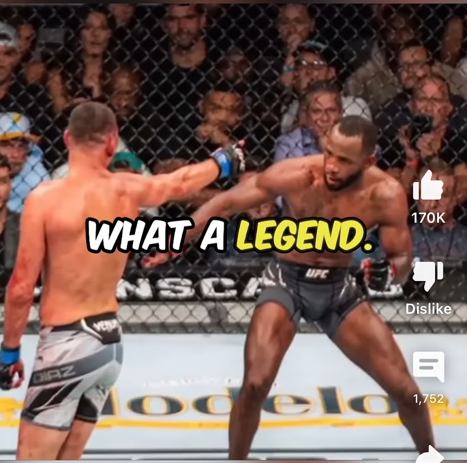 the photo shows a fight in an mma cage, with two fighters in the ring. the fighter on the left is wearing gray and black shorts and the fighter on the right is wearing black shorts with "ufc" written on it. there are several fans in the background, behind the cage. the words "what a legend" are superimposed over the fighters. the image shows a very dynamic and exciting fight, with both fighters displaying their skills and determination.