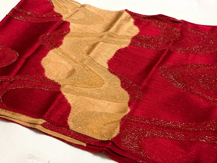 a closeup shot of a textile with a wavy design in alternating red and gold colors. the fabric has a shimmering quality, suggesting it may be made of metallic threads or sequins.