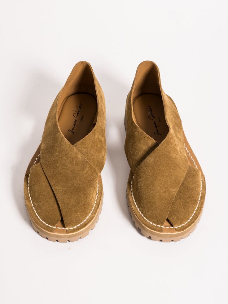 a pair of jacques chabrier women's suede sandals in a tan color are shown from an overhead perspective against a plain white background.  the sandals are flat, opentoed, and feature a crisscross strap design across the vamp.  the stitching is visible around the edges of the shoes and the label is visible inside.  the sandals appear to be made of a soft suede material and have a slightly rugged sole. the overall style is casual yet chic.