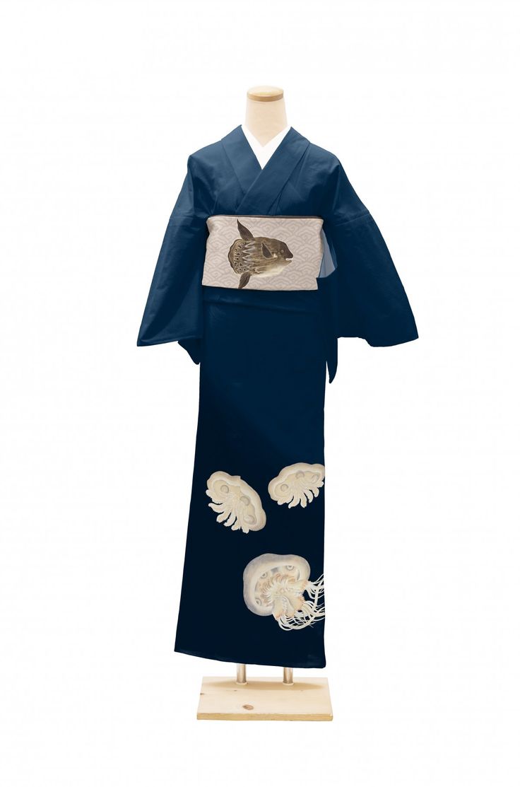 a kimono displayed on a mannequin. the kimono is dark blue and features a pufferfish design on the obi and jellyfish designs near the bottom of the robe. the mannequin is displayed on a wooden stand.