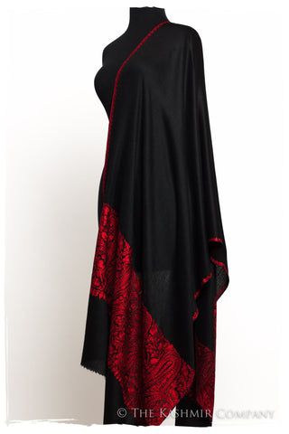 a black shawl with red floral embroidery is draped on a mannequin against a white background. the shawl is mostly black with a section of red floral embroidery covering part of the bottom and side.