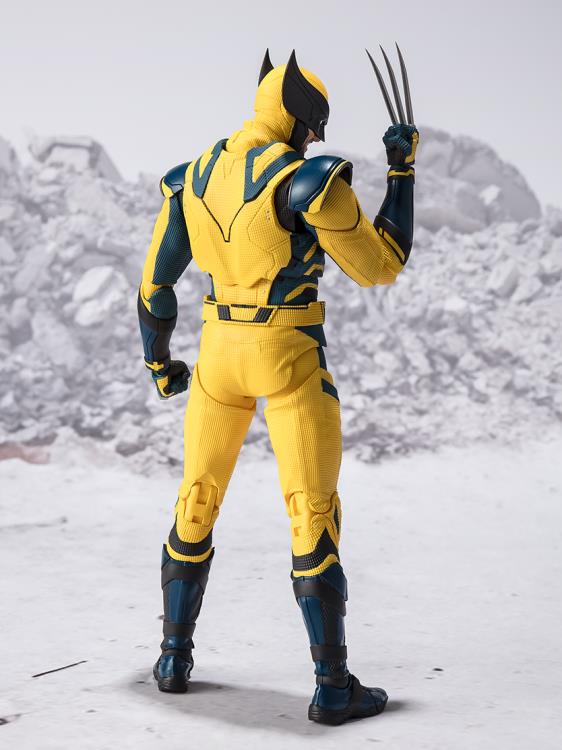 a wolverine action figure in his classic yellow and blue costume stands with his back to the camera, claws extended. the background suggests a snowy, postbattle environment.