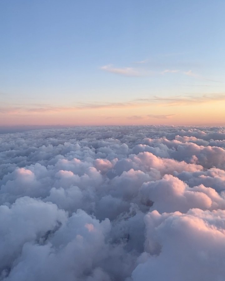 the image captures a vast expanse of fluffy white clouds stretching to the horizon, bathed in the soft pink and orange hues of a sunset or sunrise. above the clouds, the sky transitions from a light blue to a gentle pinkorange gradient. the scene evokes a sense of peace and serenity, offering an aerial view of a breathtaking natural phenomenon.