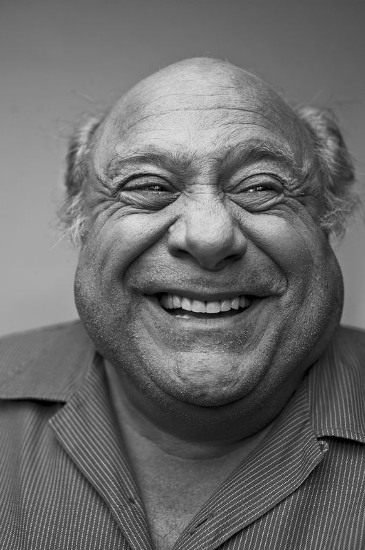 a black and white portrait of an elderly man with a white beard, wearing a striped button down shirt, and smiling.  he is facing the camera and the lighting in the image is soft.
