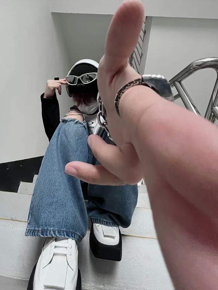 a woman with pink hair and futuristic sunglasses sits on a staircase, captured from a low angle. she is dressed in streetwear style with ripped jeans and platform shoes. the image has a cyberpunk and edgy aesthetic.