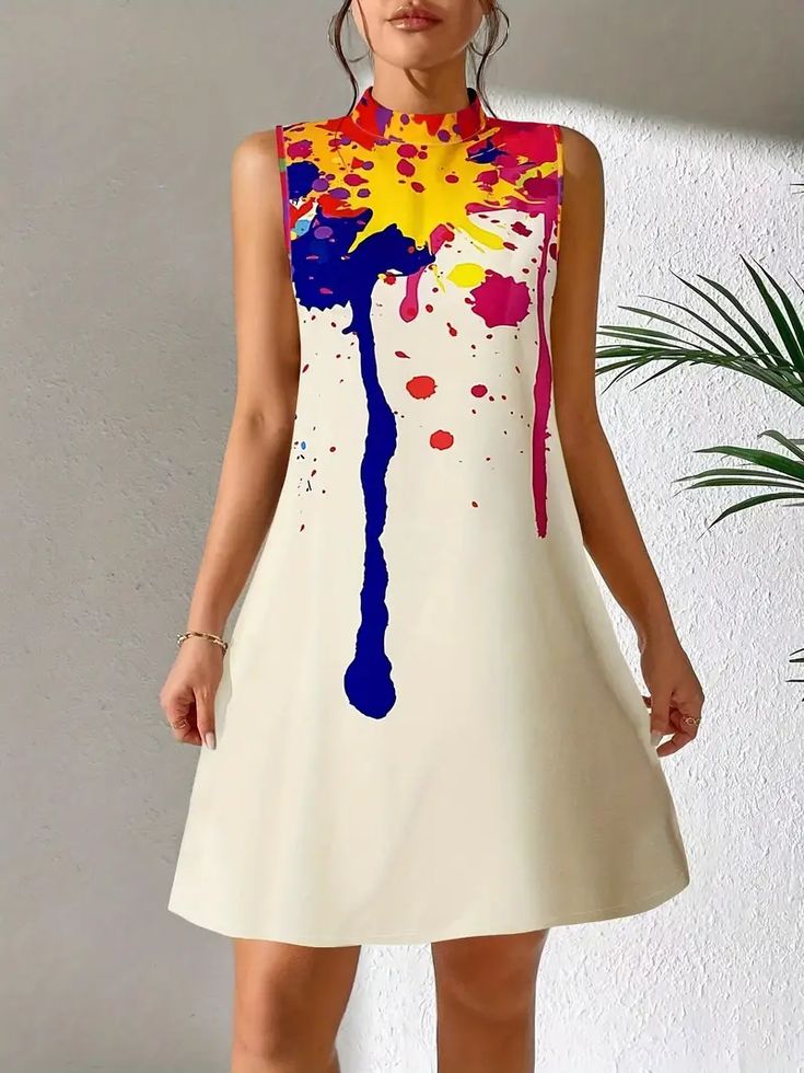a young woman with dark hair is wearing a sleeveless, short, white dress with a paint splatter design in vibrant colors. she has a neutral expression on her face, and her arms are at her side. the background is plain white. the dress is a casual, summery style.  she is standing in a studio setting.  she is posing for a picture.