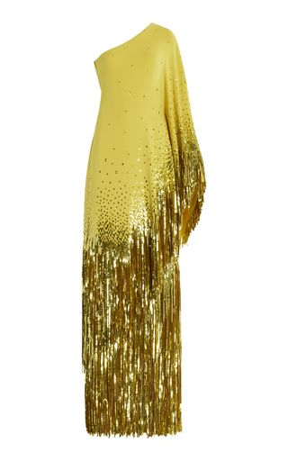 a yellow, oneshoulder evening gown with gold fringe and sequins is shown against a white background.