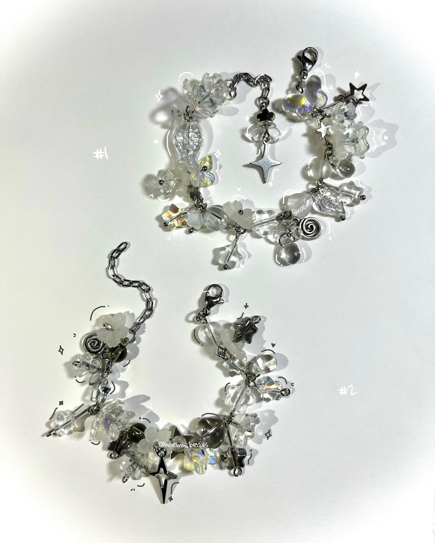 two handmade bracelets are displayed on a white background. the bracelets are adorned with clear beads, silver chains, and various charms, including stars and floral shapes. they are labeled as "#1" and "#2."