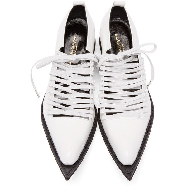a pair of comme des garçons white leather pointedtoe boots with laceup detailing. the boots are a pale white color and have a sharp pointed toe.  the laces are thin and white, creating a crisscross pattern across the vamp. the sole appears to be black. the shoes are displayed from a topdown perspective.