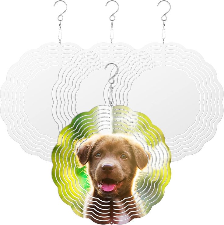 the image shows three wind spinners hanging from hooks. the wind spinner in the front has an image of a brown puppy with its tongue sticking out. the background of the puppy picture is green. the other two wind spinners are white and have a wavy pattern.