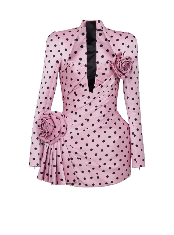 a pink polka dot minidress with long sleeves, a high neck, and floral embellishments. the dress has a black trim down the front and is cinched at the waist.