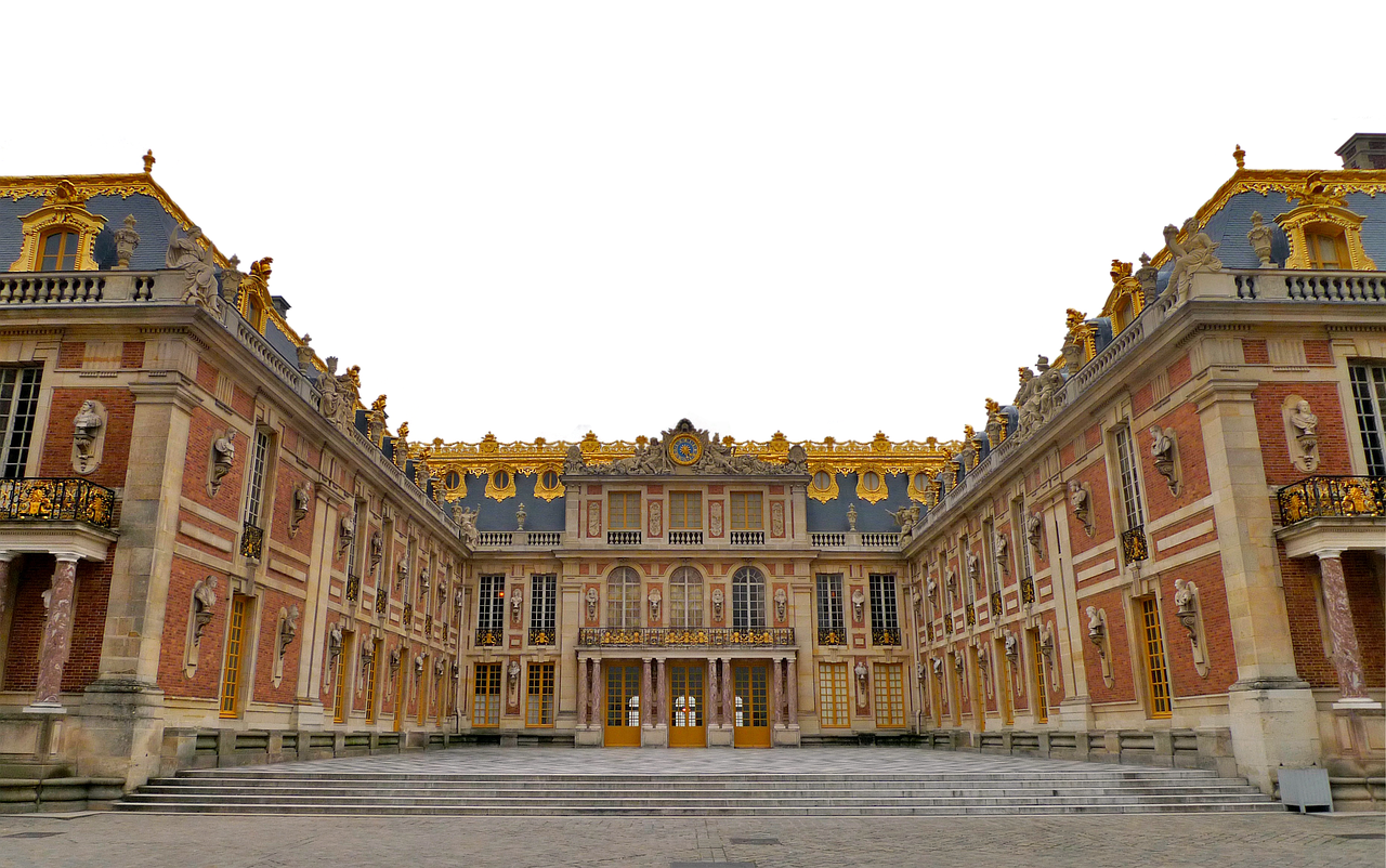 the image showcases the palace of versailles from a groundlevel perspective, emphasizing its grandeur. the building's facade features ornate details, including gold accents and classical architectural elements. a large courtyard with steps leads up to the palace. the image highlights the palace's scale and intricate design.