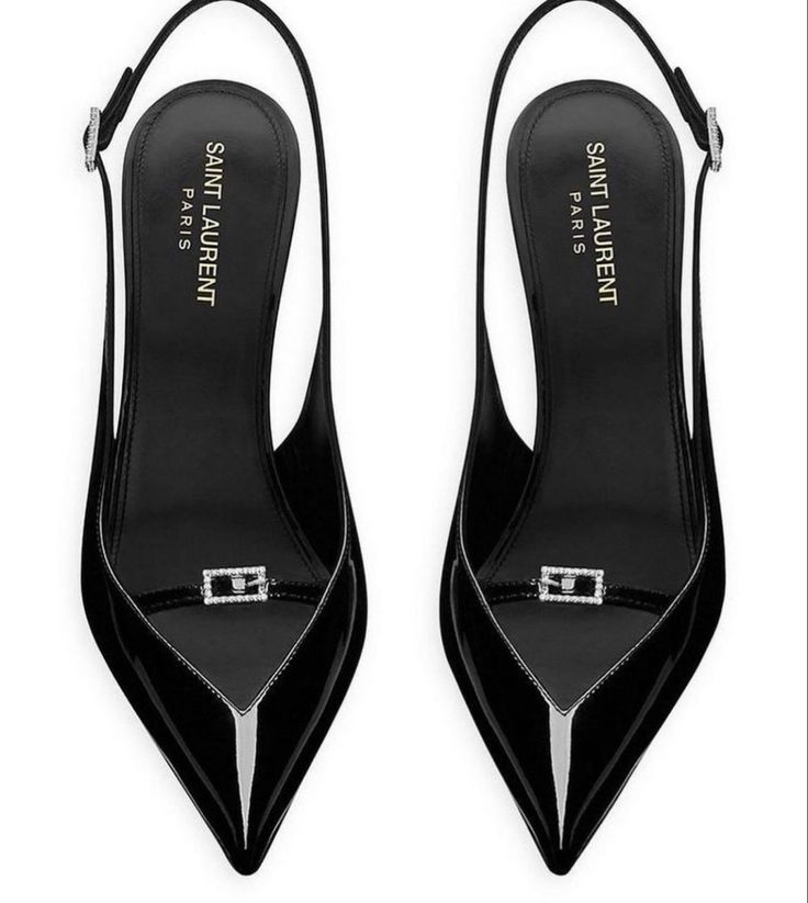 an overhead shot of a pair of black patent leather saint laurent slingback pumps. the shoes are pointedtoe heels with a delicate crystal buckle detail across the vamp.  the insoles are visible, showcasing the "saint laurent paris" branding.  the shoes appear to be new and unworn.