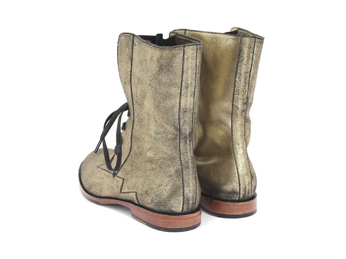 a pair of gold suede boots with black laces are seen from the back.