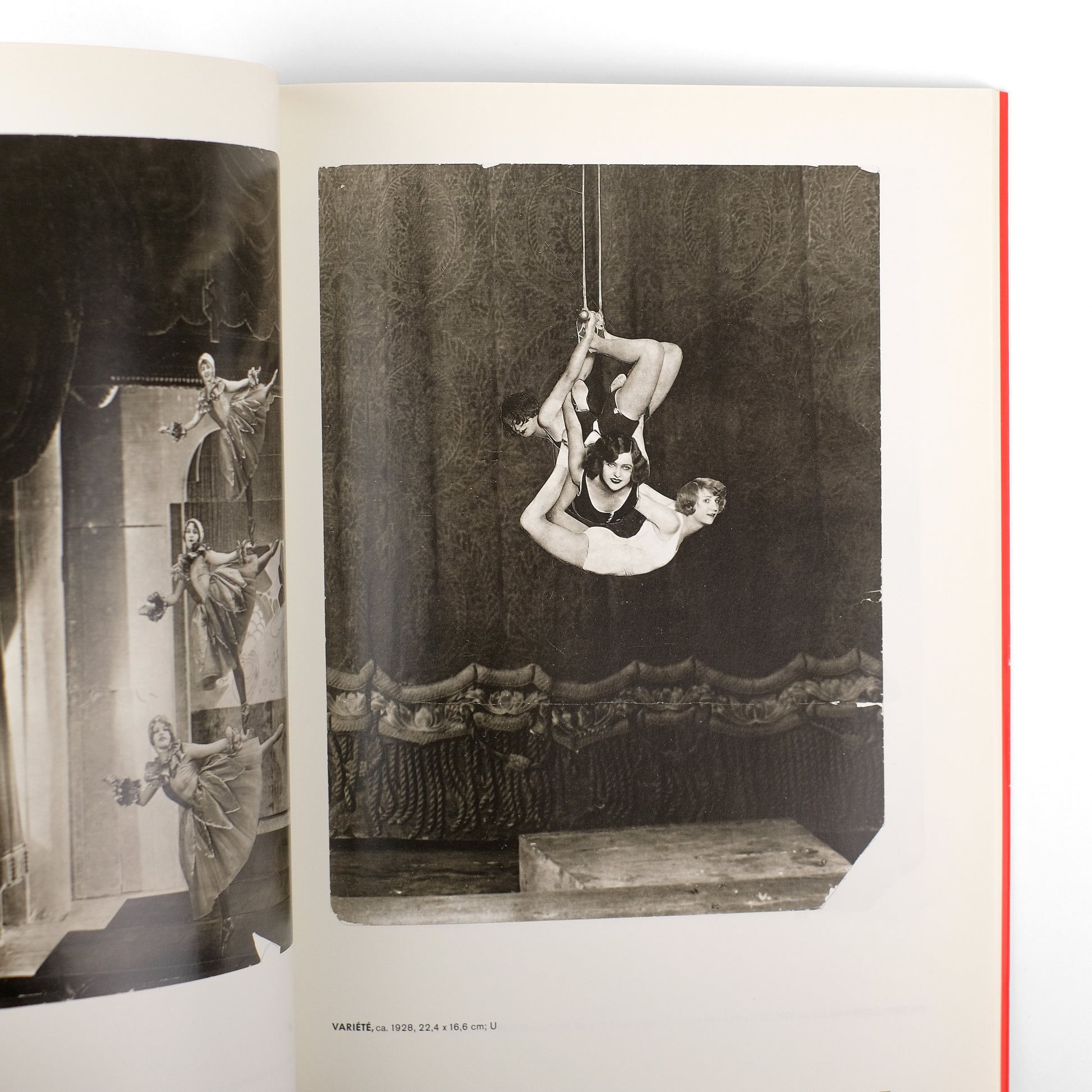 spread from a photo book featuring a black and white photograph as the main image. the photo shows three women acrobats performing an aerial act. they are suspended upside down from a rope, their bodies intertwined.  the background is a dark stage with curtains.  the page shows other smaller images of similar performers.  the style suggests a 1920s circus or vaudeville setting, with potential use of collage or multiple exposure techniques. the overall aesthetic is vintage and art decoinfluenced.