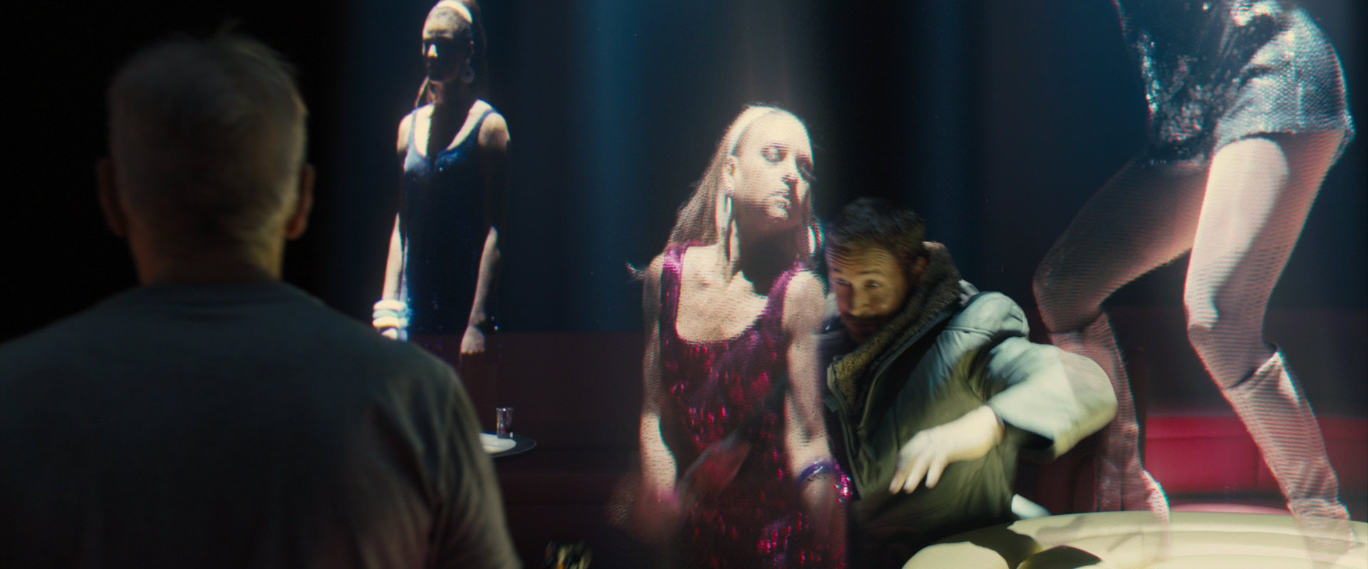 the image shows a group of people watching a holographic performance in a dark nightclub. the hologram depicts four dancers in revealing outfits, illuminated by blue and red spotlights. the scene has a futuristic and digital aesthetic.