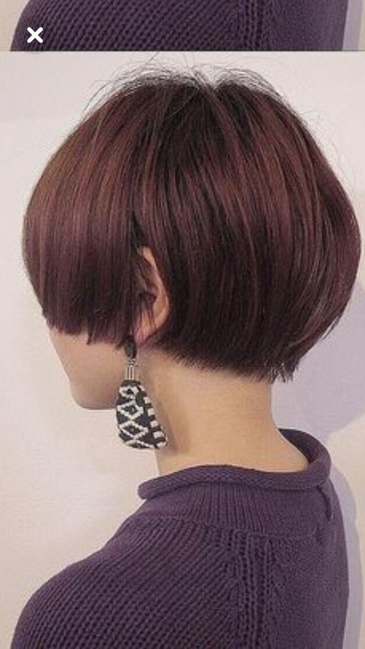 a woman with short bob hair wearing a purple sweater with an earring and looking away from the camera.