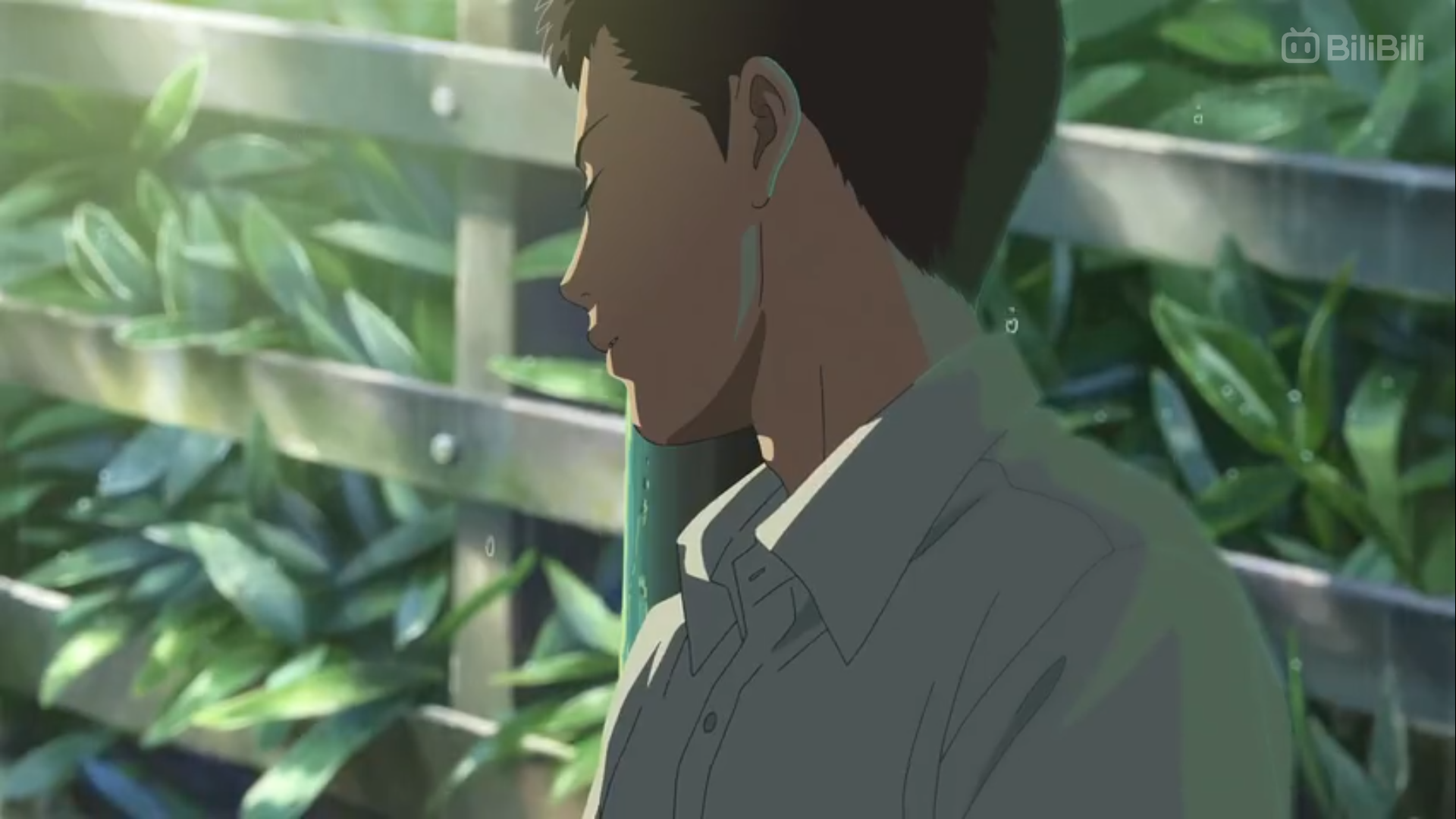 the image shows a young man in profile view, his eyes closed and a serene expression on his face. he's wearing a white shirt and is positioned against a backdrop of lush green foliage and a wooden fence. the lighting is soft and natural, suggesting a peaceful and reflective mood.