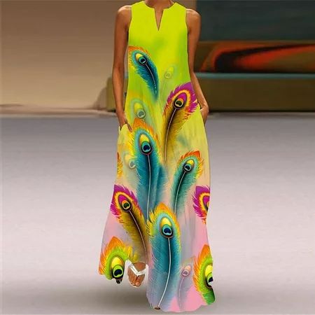 he image shows a model wearing a vibrant women's maxi dress. the dress is sleeveless with a vneckline and features a striking peacock feather print in various bright colors on a light yellow background. the dress has a loose, comfortable fit and appears suitable for warm weather or casual occasions. the model is standing on a runway or catwalk, showcasing the dress's full length. the background features blurred elements, drawing focus to the dress itself.