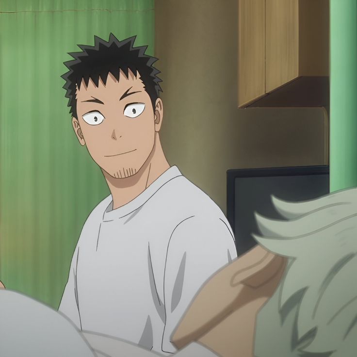 two men are pictured. one is wearing a white tshirt and is smiling slightly at the other man. the other man is laying down and his face is not visible.  they appear to be in a bedroom.